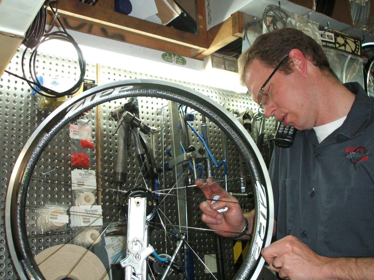 Final truing a Zipp 303 carbon wheel in the truing stand while taking a customer call