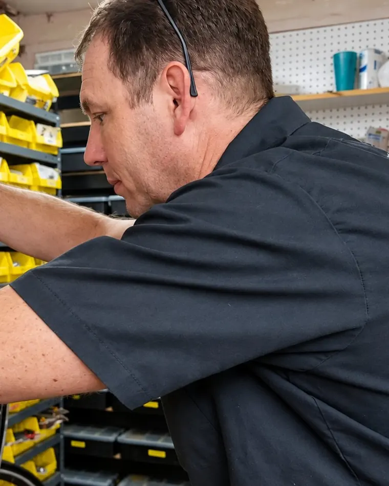 A wheelbuilder reaching for parts on the shop shelves